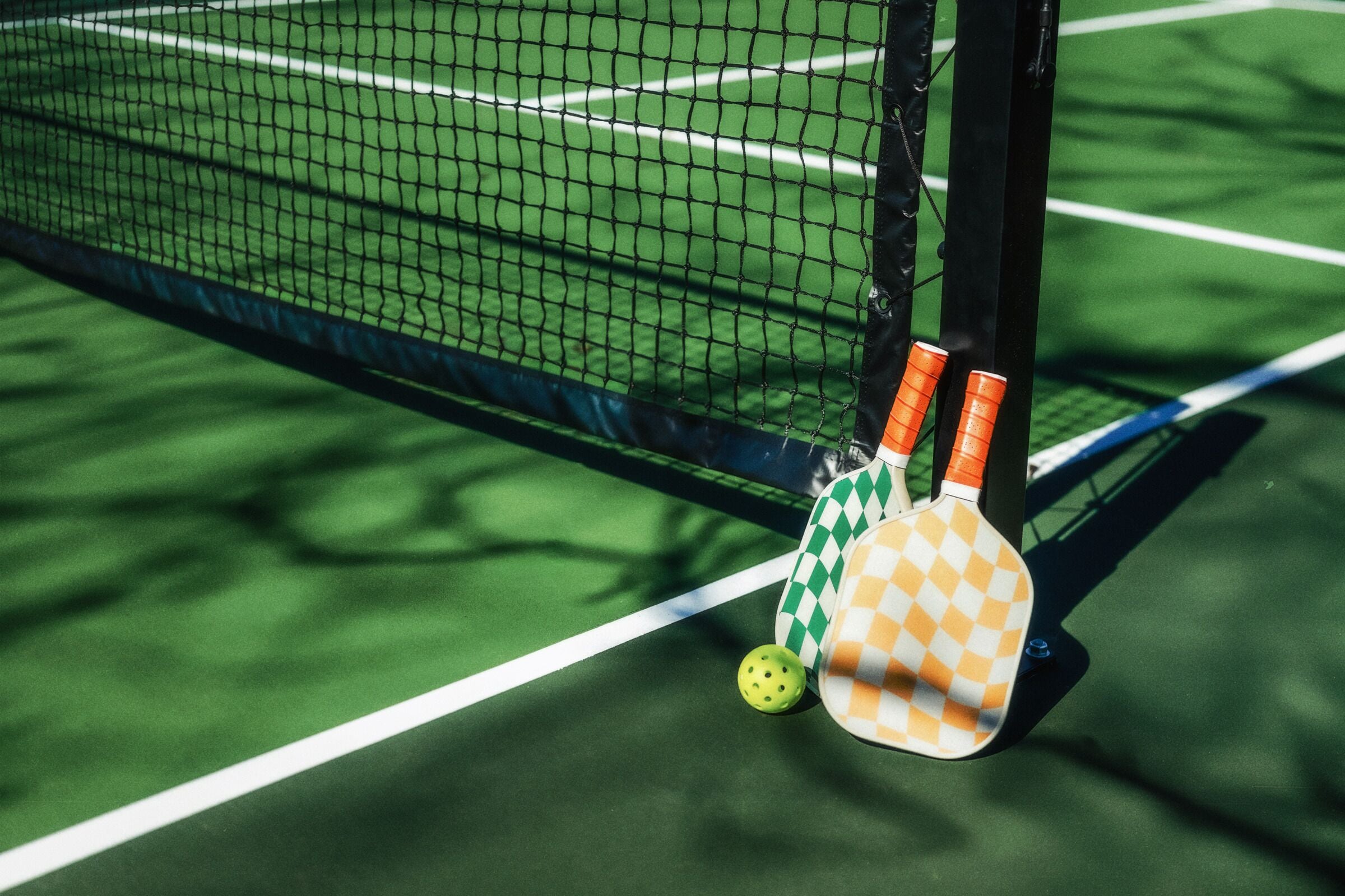 A tennis court with a net, a ball, and two tennis rackets.
