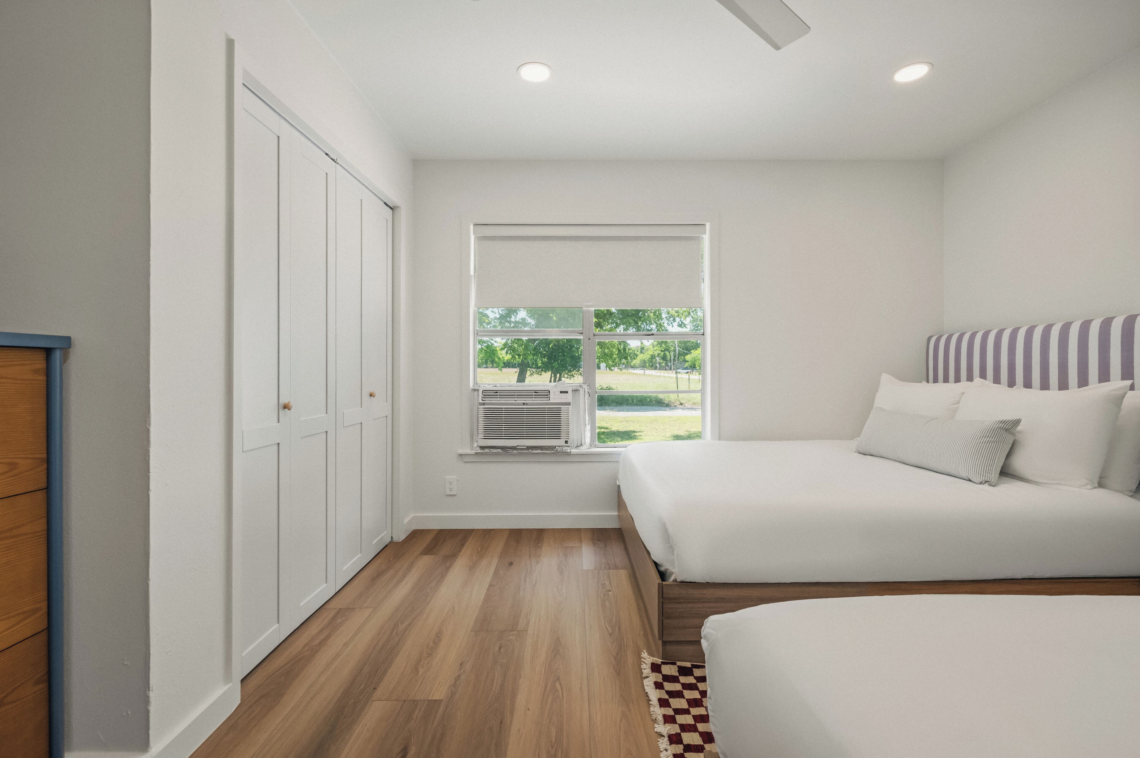 A bedroom with a window, a bed, a wardrobe, and a ceiling fan.
