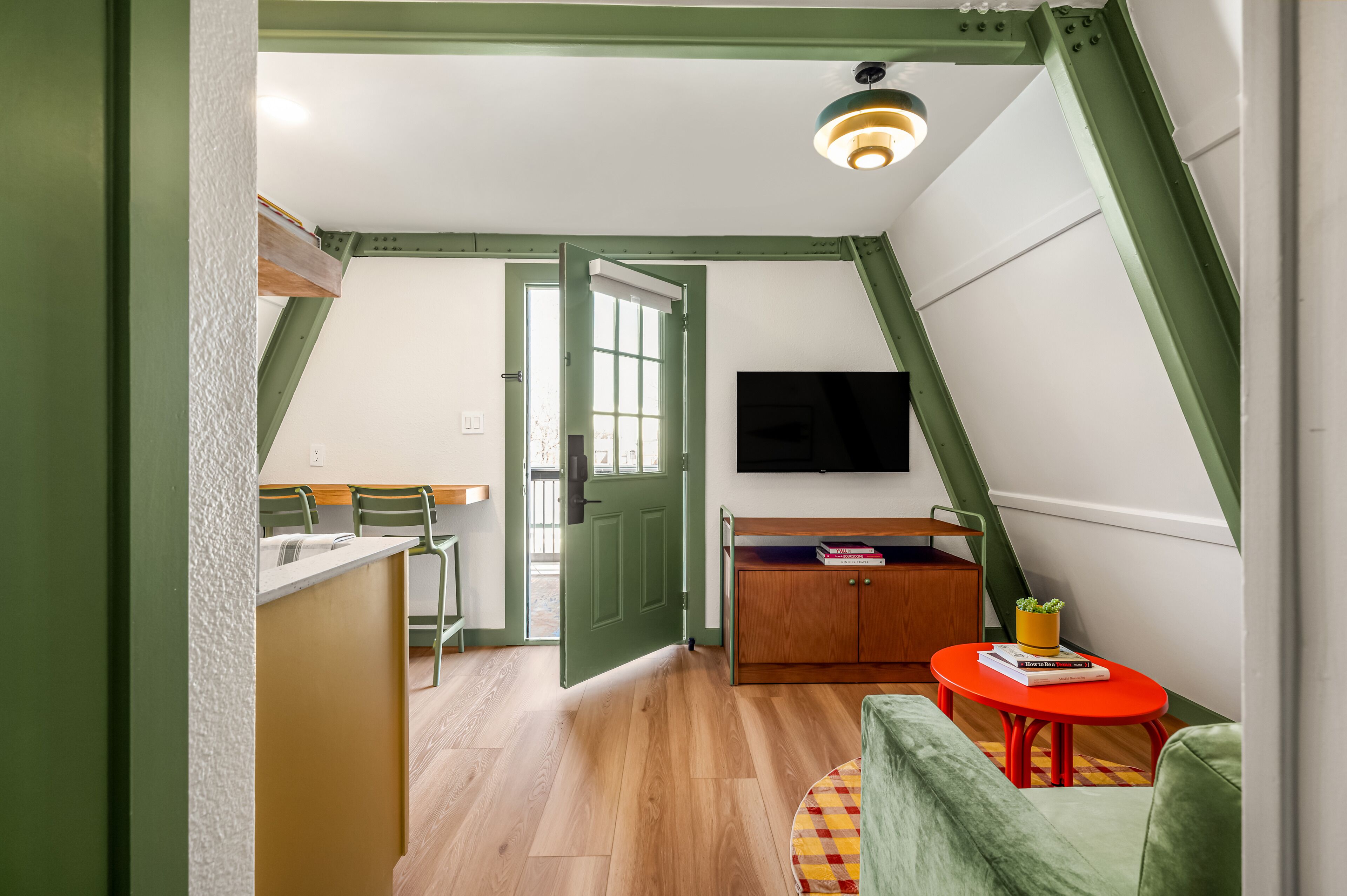 A room with a dining area, a sofa, a TV, and a small table with books.