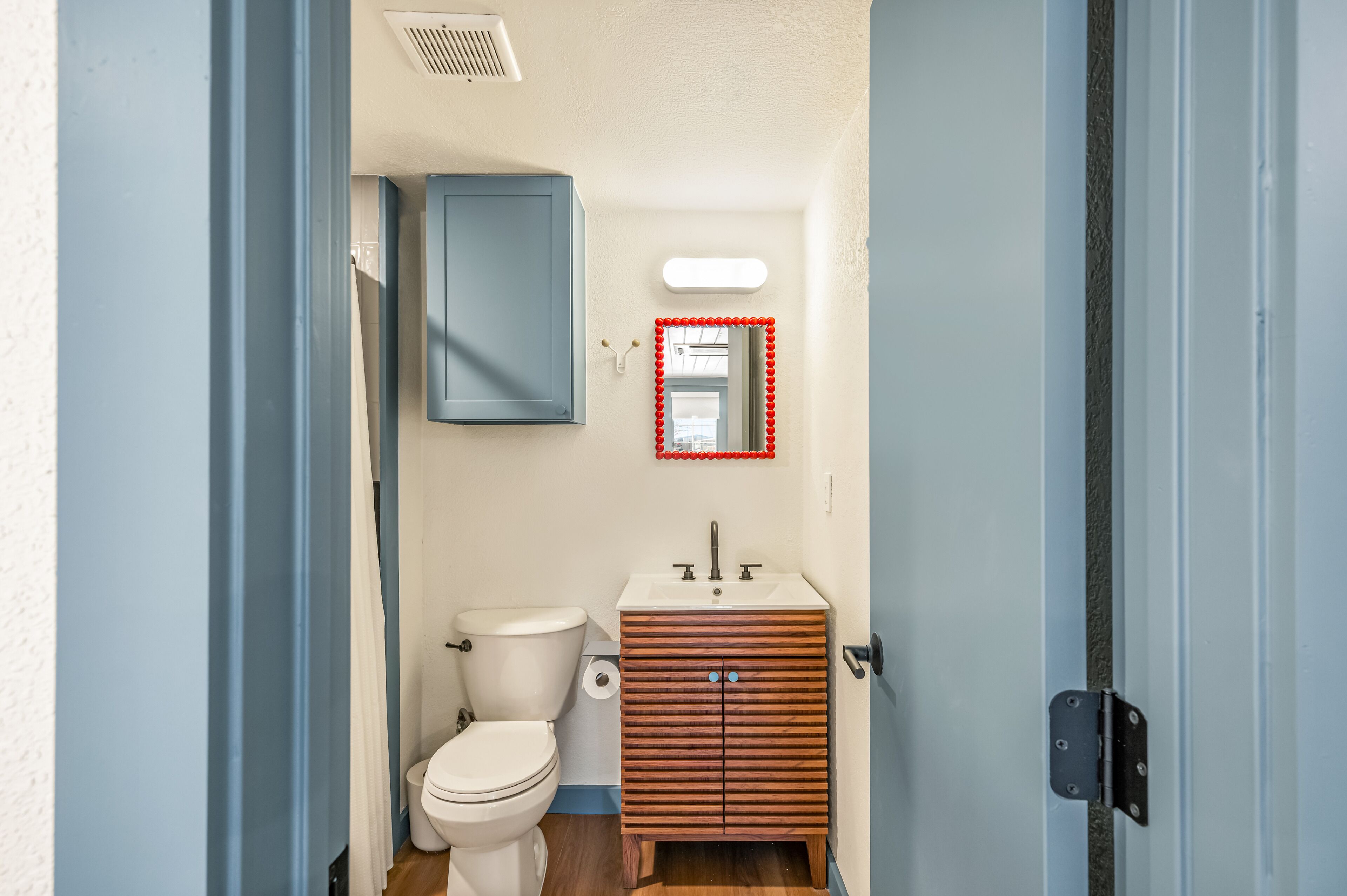 A bathroom with a toilet, sink, and wooden cabinet.