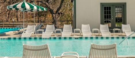 A pool area with white lounge chairs and a green and white striped umbrella.