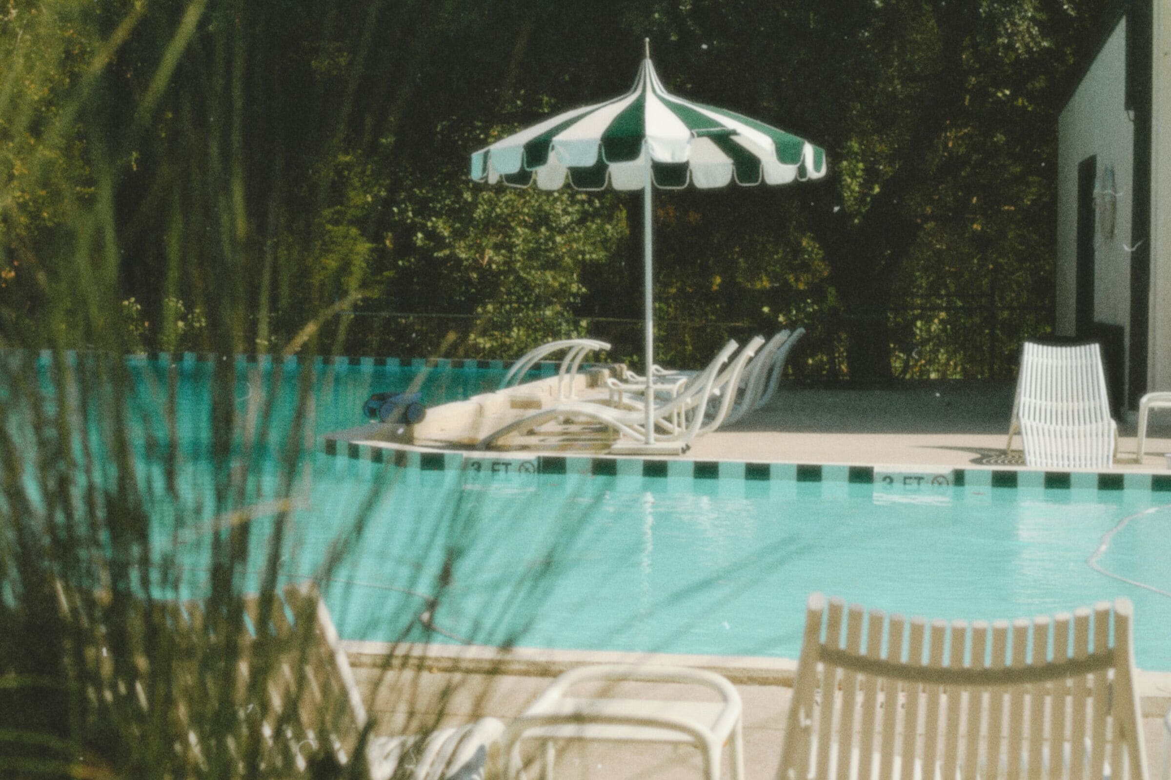 Une piscine avec des chaises longues et un parasol à rayures.