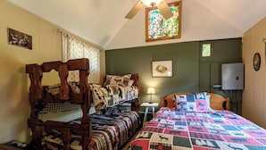A cozy bedroom with two wooden beds, a quilted bedspread, a small table, and a wall-mounted lamp.