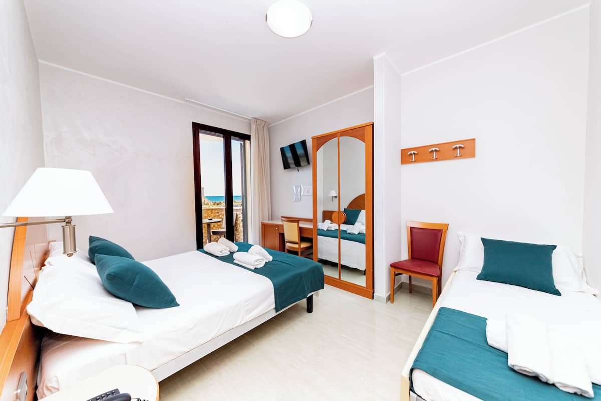 A hotel room with two beds, a desk, a chair, a TV, and a large mirror.