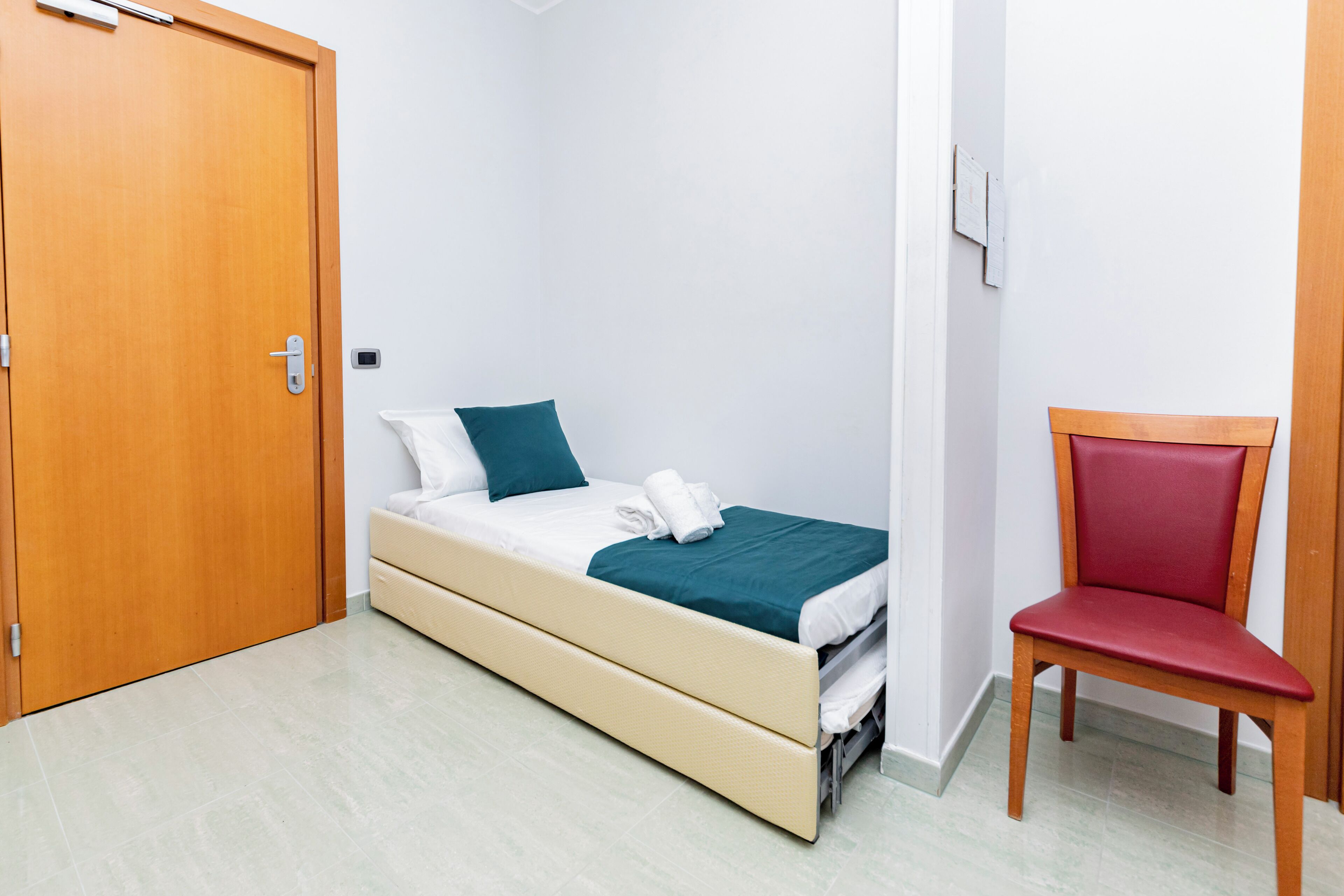 Un dormitorio con una cama, una silla y una puerta de madera.