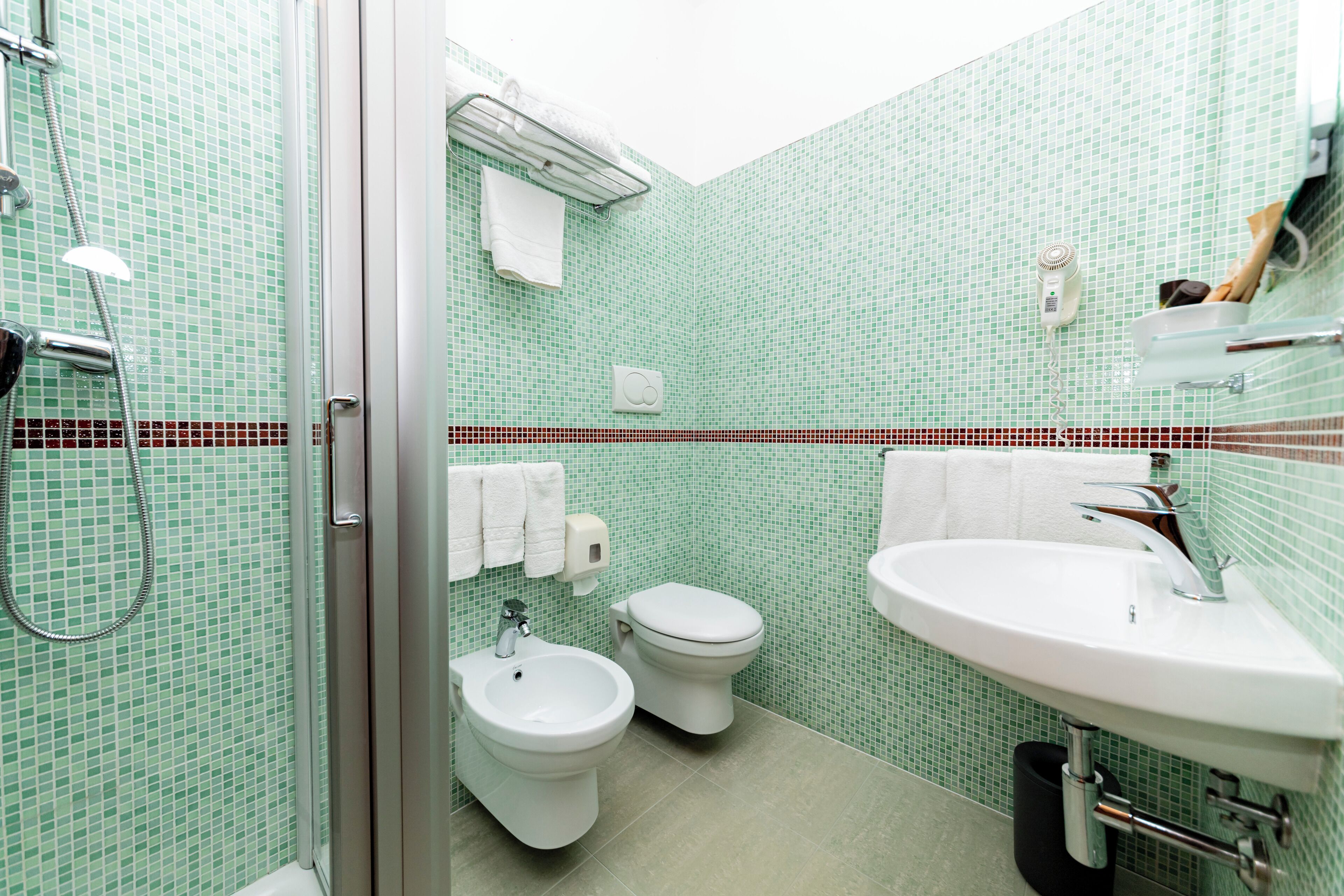 A bathroom with a shower, bidet, toilet, and sink.
