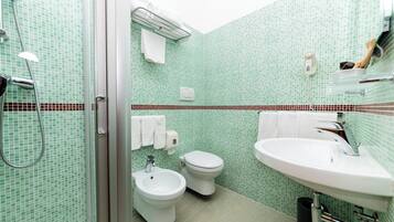 A bathroom with a shower, bidet, toilet, and sink.