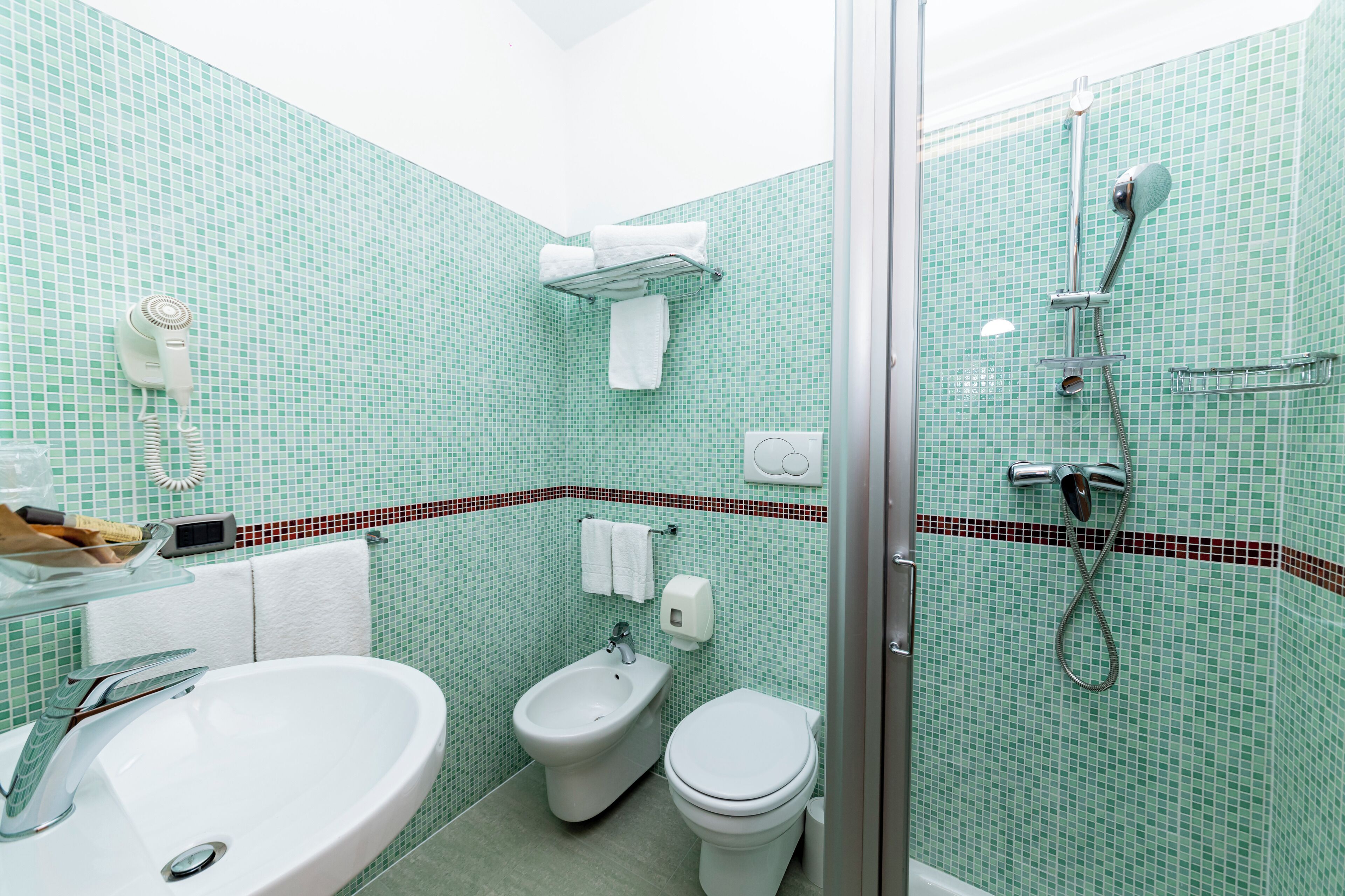 A bathroom with a sink, bidet, toilet, and shower.