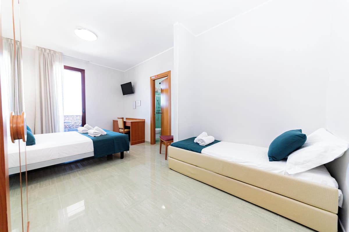 A hotel room with two beds, a desk, and a chair.