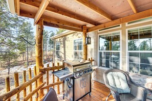 Un espace extérieur abrité comprenant un barbecue, une chaise en osier et une terrasse en bois.
