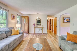 Una sala de estar con un sofá, una mesa de centro y un pasillo que conduce a una puerta.