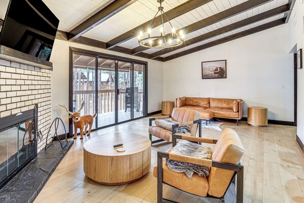 A spacious living area with a fireplace, leather sofa, and a round wooden coffee table. - Sledding Thrills & Fireside Warmth: Pinetop Home (Pinetop)