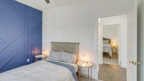 A bedroom with a bed, bedside tables, a ceiling fan, and a door leading to another room.