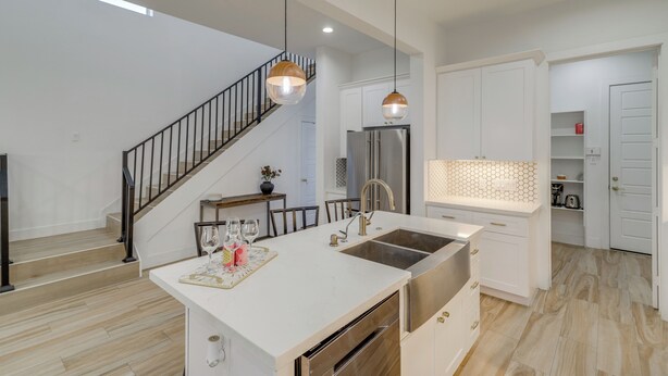 A modern kitchen with a central island, stainless steel appliances, and pendant lighting.