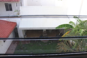 Une cour avec un bâtiment blanc, un toit rouge et quelques plantes.