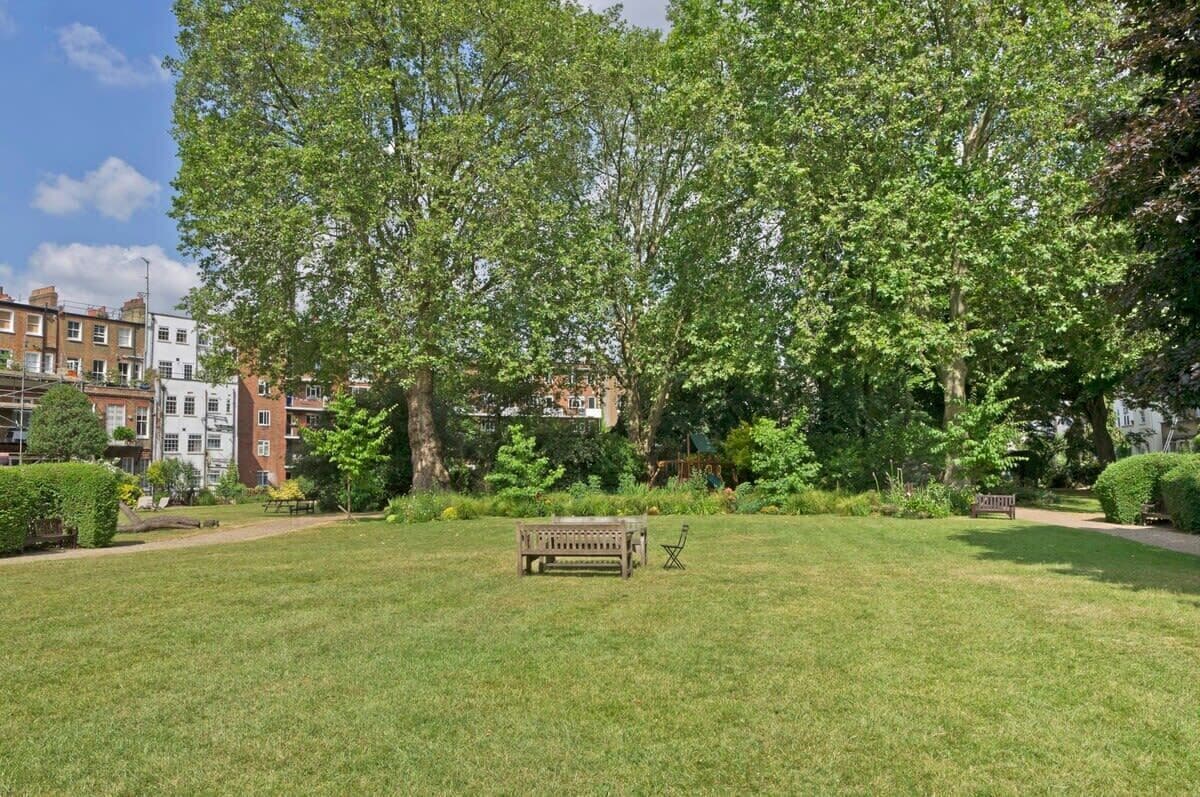 A park with a bench, trees, and a pathway.