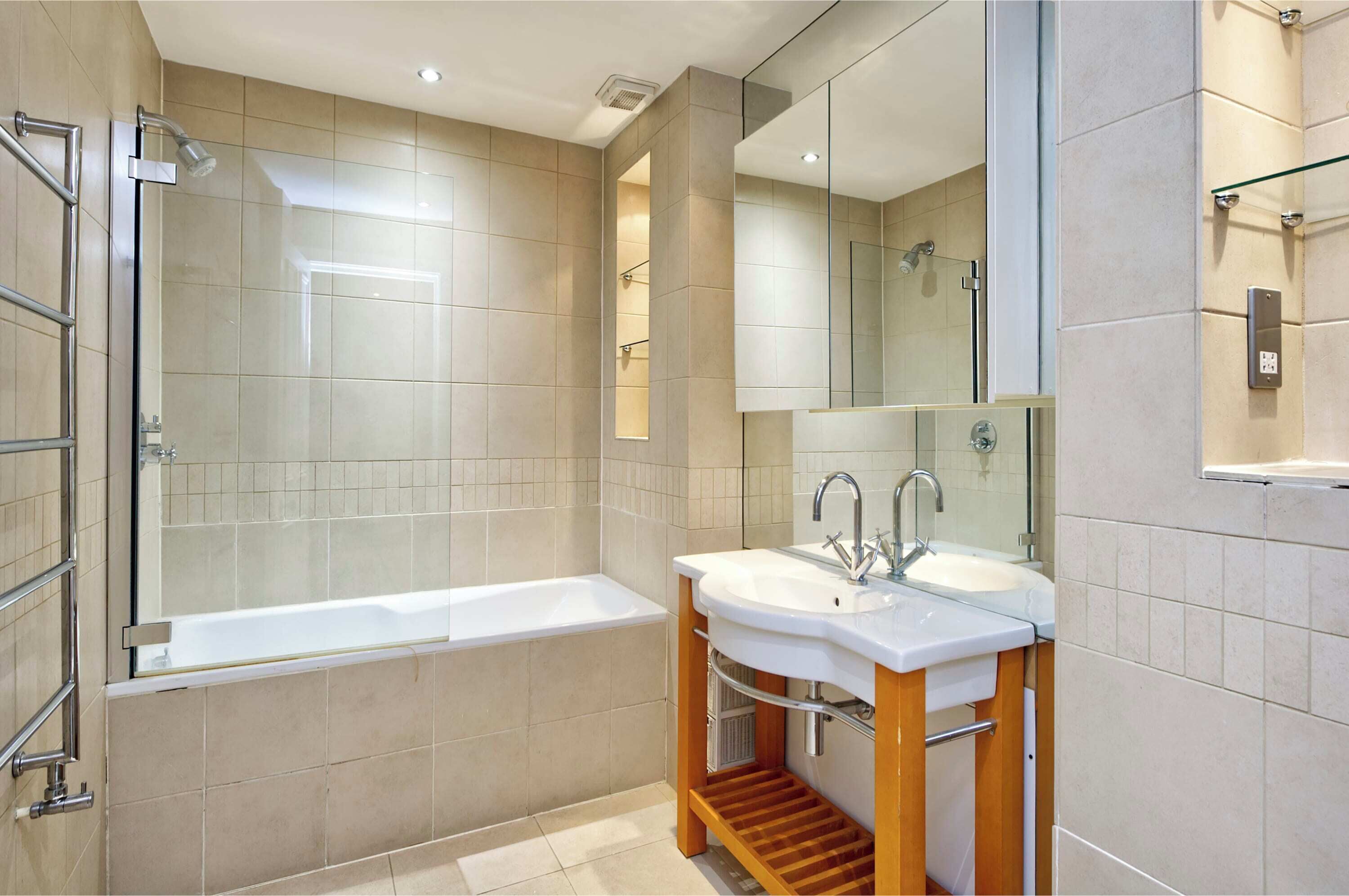 Un baño moderno con ducha envuelta en vidrio, una bañera blanca y un tocador con lavamanos y espejo.