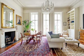 Ein geräumiges Wohnzimmer mit Kamin, einer Kristallleuchter und einem großen Fenster.