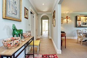 Stunning hallway leads to a dining area with framed artworks, a decorative horse sculpture, and a console table.