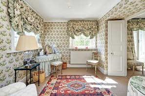 Relax in a classic room with a comfortable seating area, patterned rug, and traditional floral wallpaper.