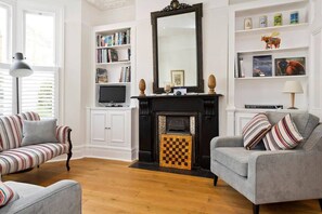 A living room with a fireplace, a bookshelf, and two sofas. - Spacious 4 Bed House, Battersea (London)
