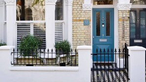 A traditional townhouse with a blue door, white columns, and a black and white tiled entrance. - Spacious 4 Bed House, Battersea (London)