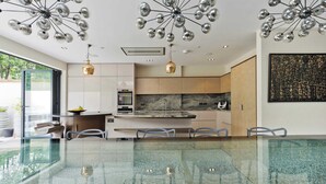 A modern kitchen with a glass dining table, stainless steel appliances, and pendant lighting. - 7bed Notting Hill W/garden, Games Room & Parking (London)
