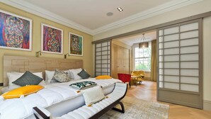 A modern bedroom with a large bed, a chaise lounge, and a sliding glass door leading to a balcony. - 7bed Notting Hill W/garden, Games Room & Parking (London)