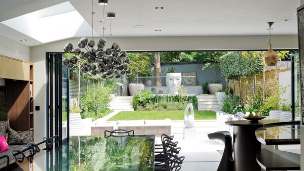A modern interior with a glass dining table, black chairs, and a view of a well-maintained garden through large windows. - 7bed Notting Hill W/garden, Games Room & Parking (London)