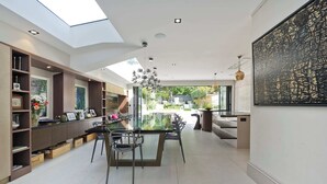A modern kitchen with a glass dining table, built-in shelving, and a view to the outdoors. - 7bed Notting Hill W/garden, Games Room & Parking (London)