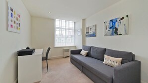 Un salon moderne avec un canapé gris, un meuble blanc et un radiateur.