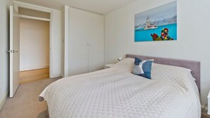 Une chambre à coucher avec un lit, une table de chevet, un tableau et une armoire.