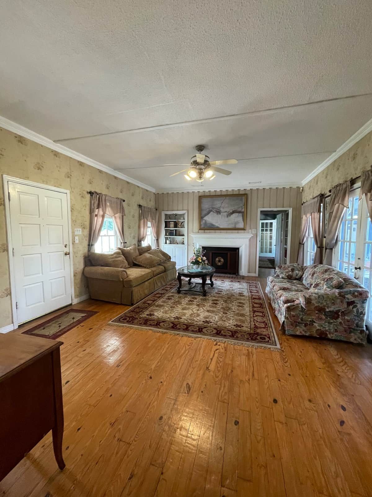A living room with hardwood flooring, a sofa, a coffee table, and a fireplace.