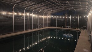 An indoor swimming pool with a metal roof and string lights. - Spacious country oasis:Swim,BBQ, Attend Weddings!Close to venues in Hill Country (Austin)