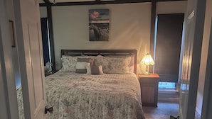 A bedroom with a bed, a nightstand, a lamp, and a painting on the wall. - Spacious country oasis:Swim,BBQ, Attend Weddings!Close to venues in Hill Country (Austin)