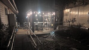 A covered outdoor seating area with tables and chairs, a metal railing, and string lights. - Spacious country oasis:Swim,BBQ, Attend Weddings!Close to venues in Hill Country (Austin)