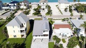 Zona residencial costera con casas, playa y palmeras.