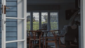 An open door leading to a dining area with a table and chairs, a rug on the floor, and a doormat in front.
