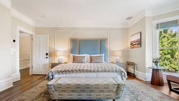A bedroom with a large bed, a bench, a nightstand, and a window with a view.