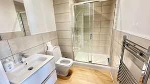 A modern bathroom with a glass-enclosed shower, a white sink, and a toilet. - Up to 40 Percent Off Old Trafford Modern Apartment (Manchester)