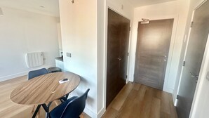 A modern living room with a round wooden table, a blue chair, and a dark wooden door. - Up to 40 Percent Off Old Trafford Modern Apartment (Manchester)