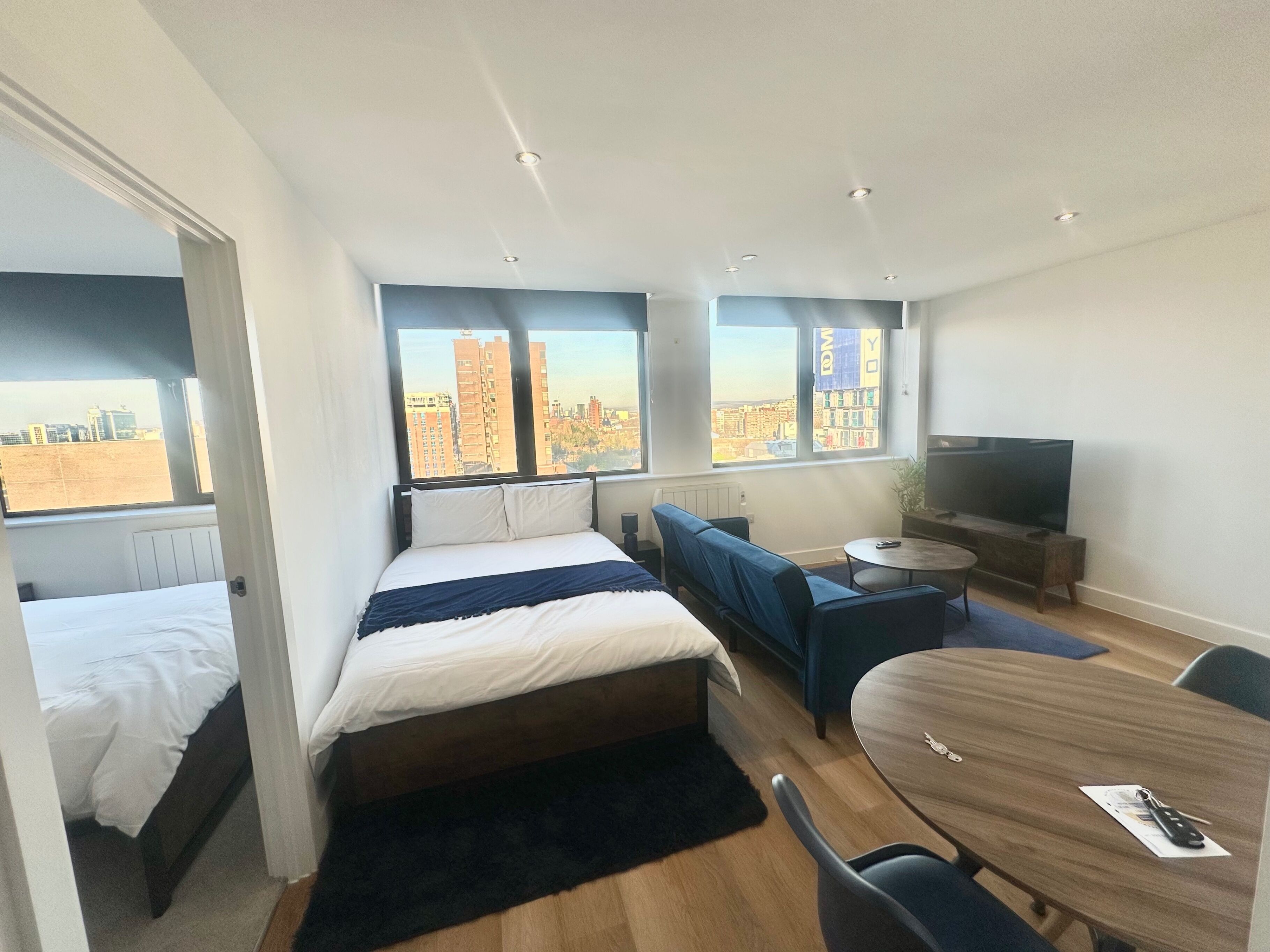 Ein modernes Hotelzimmer mit Bett, Sofa, Fernseher und Esstisch.