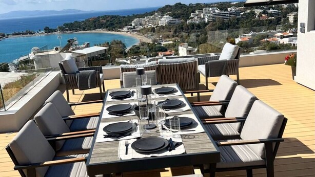 Un área de comedor al aire libre con una mesa para cuatro, con vistas a la costa.