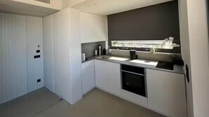 Una cocina moderna con armarios blancos, horno integrado y ventana sobre el fregadero.