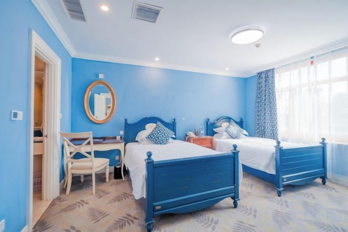 Un dormitorio con dos camas, un escritorio, una silla y una ventana con cortinas.