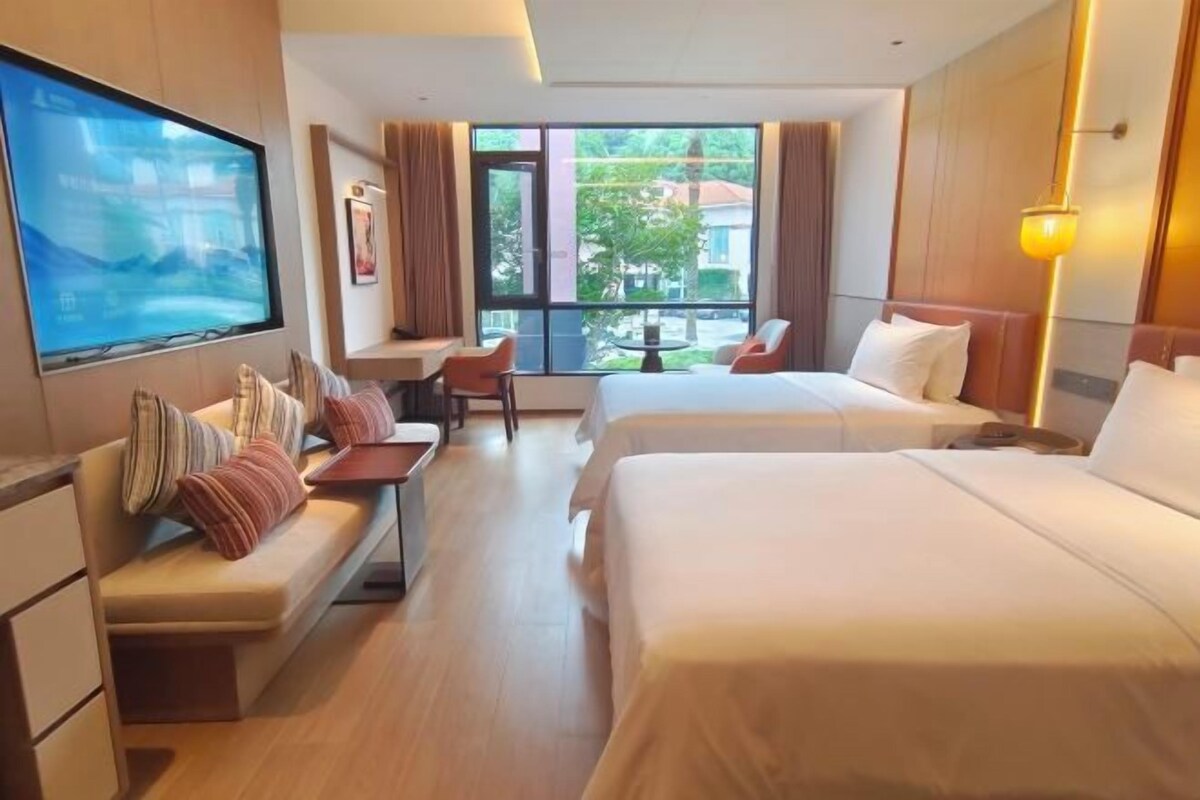 A hotel room with a bed, a sofa, a desk, and a TV.