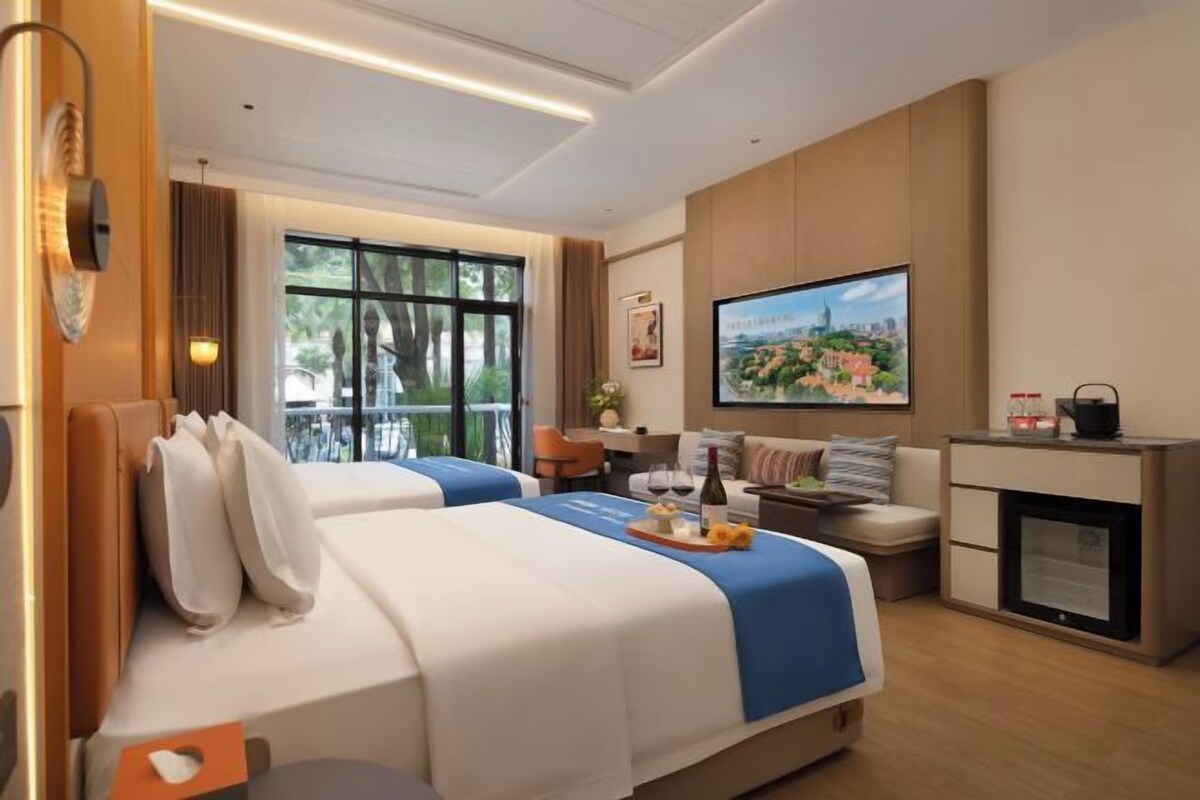 A hotel room with two beds, a television, a fireplace, and a balcony.