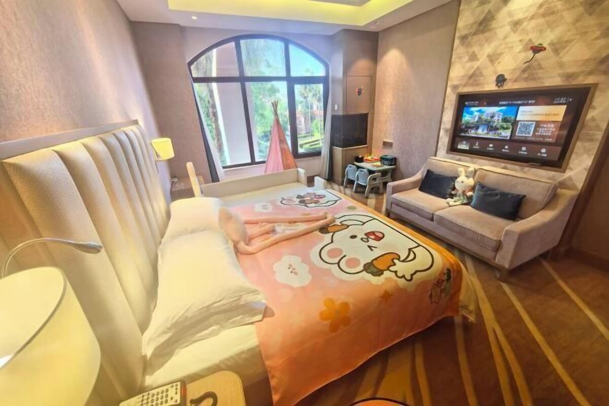 A hotel room with a bed, a sofa, a TV, and a window with a view.