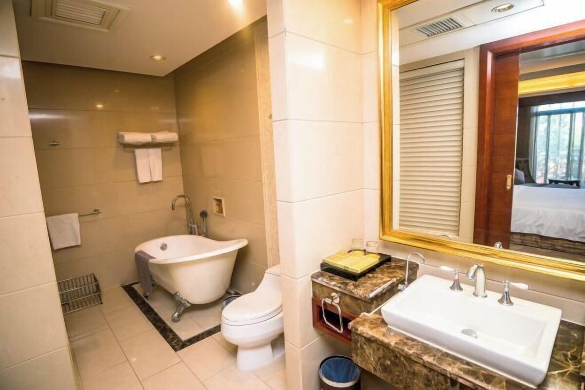 A modern bathroom with a bathtub, toilet, sink, and a large mirror.