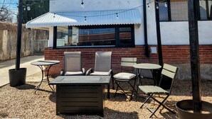 An outdoor seating area with tables and chairs, a brick wall, and string lights. - Charming 1938 Pueblo Home with Game Room, Firepit and Boho Bedroom (Pueblo)